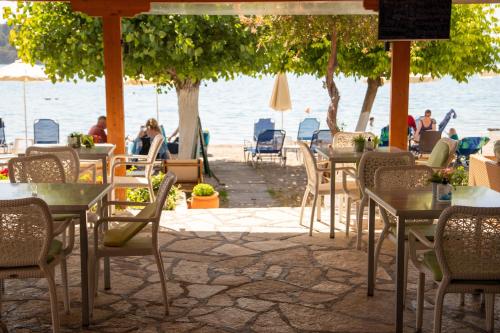 ein Restaurant im Freien mit Tischen, Stühlen und Wasser in der Unterkunft Hotel Nydri Beach in Nydri