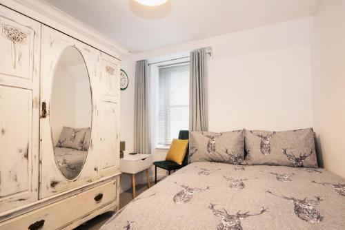 a bedroom with a bed with a dresser and a mirror at Unique 2 Bedroom Flat Kirrie Scotland in Kirriemuir