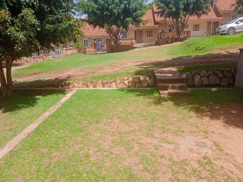 a yard with a stone wall in front of a house at Abid's Homestay in Kampala