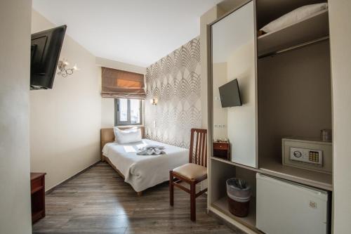 Habitación pequeña con cama y espejo. en Athens Golden City Hotel, en Atenas