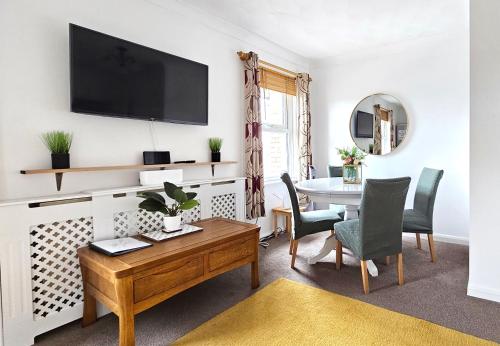 a living room with a table and a television on a wall at 2 bed apt w/ private parking close to town centre in Huntingdon