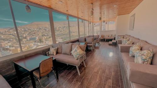 a large room with couches and tables and large windows at Beit Alshabaan Inn in Wadi Musa
