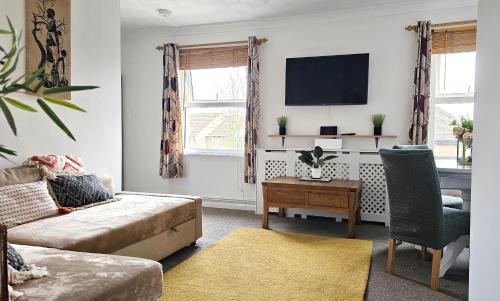 ein Wohnzimmer mit einem Sofa und einem Tisch in der Unterkunft 2 bed apt w/ private parking close to town centre in Huntingdon