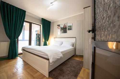 a bedroom with a bed with green curtains and a television at Apartament S46 in Roman
