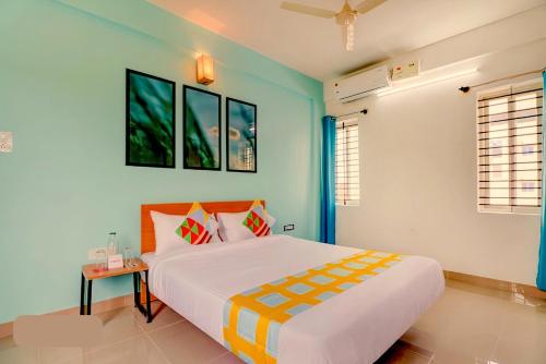 a bedroom with a large white bed and blue walls at Vrishi Suites in Bangalore