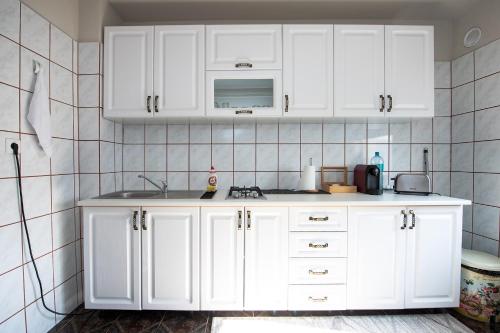 a white kitchen with white cabinets and a microwave at Apartament S46 in Roman
