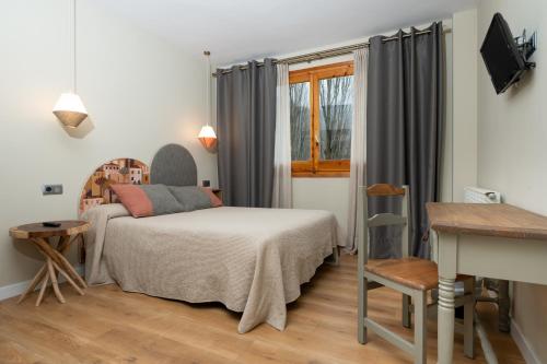 a bedroom with a bed and a desk and a window at Hotel de Montaña El Mirador in Broto