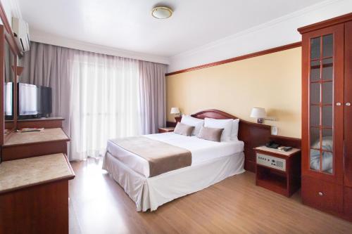 a hotel room with a large bed and a television at Jandaia Turismo Hotel in Santana do Livramento