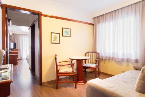 a room with a bed and a table and chairs at Jandaia Turismo Hotel in Santana do Livramento