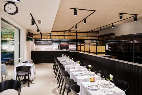 a dining room with white tables and chairs and a clock at La Maison in Adyliget