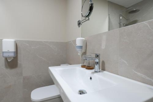 a bathroom with a white sink and a mirror at Hotel de Montaña El Mirador in Broto