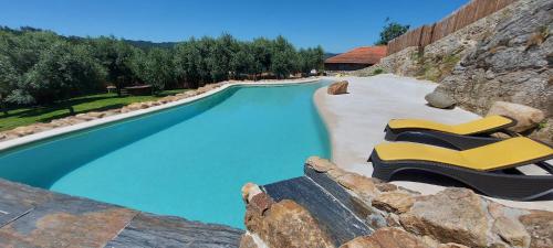 a swimming pool with two yellow lounge chairs next to it at Casa Guardião do Castelo in Celorico de Basto
