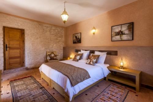 a bedroom with a large bed and a wooden floor at Charmante Villa Riad Dharma in Essaouira