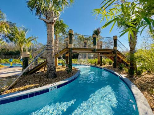 a swimming pool with a wooden bridge and a wooden walkway at Magical Themed Home - Disney 15 min in Kissimmee