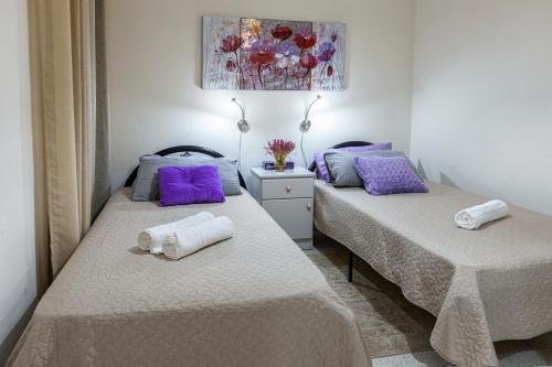 - 2 lits dans une chambre avec des oreillers violets et violets dans l'établissement Seaside Flat with Scenic Country Views, à Mellieħa