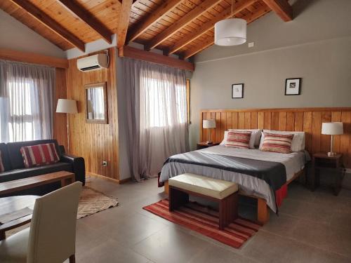 1 dormitorio con 1 cama y sala de estar en Las Bayas Home Suites en Esquel