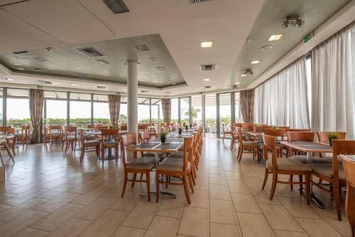un restaurante con mesas, sillas y ventanas en Athens Golden City Hotel, en Atenas