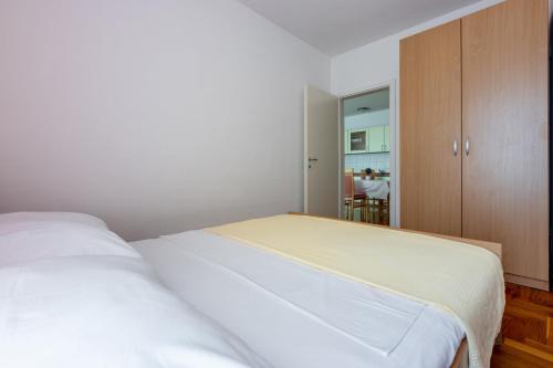 um quarto com uma cama branca e um armário de madeira em Pasalic Novi em Novi Vinodolski