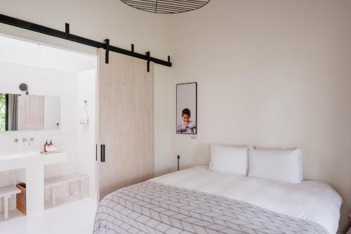 a white bedroom with a bed and a sink at Good Hotel Antigua in Antigua Guatemala