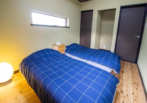 a bedroom with two blue beds and a window at 予約制薪割りBBQ可能! 青の洞門から車で15分 l 四季折々の自然が楽しめる農泊古民家 鍋屋 in Sugihata