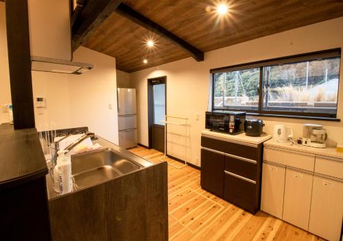 a large kitchen with a sink and a counter at 予約制薪割りBBQ可能! 青の洞門から車で15分 l 四季折々の自然が楽しめる農泊古民家 鍋屋 in Sugihata