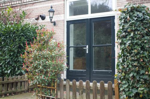 eine schwarze Tür an einem Haus mit einem Zaun in der Unterkunft B&B de Fruithof in Heteren