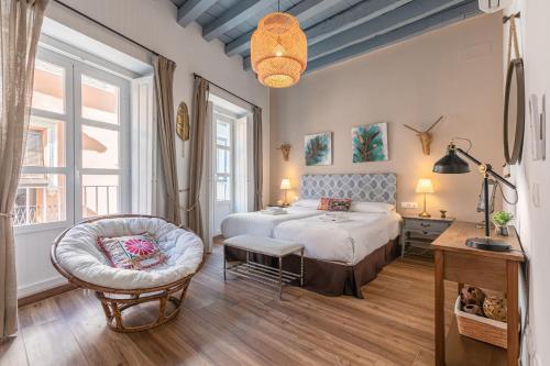 a bedroom with a large bed and a chair at Green-Apartments Mansión Blue Catedral in Seville