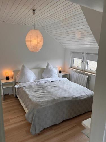 ein weißes Schlafzimmer mit einem großen Bett und einer Lampe in der Unterkunft Rust-Appartements-II-Marienrode in Hildesheim
