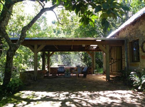 a covered patio with two chairs and a table at KLIPINNIBOS Nature Farm in Schoemanskloof