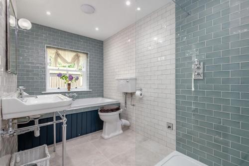 y baño con lavabo, aseo y azulejos azules. en Burnside - gorgeous romantic cottage for 2 en Monzie