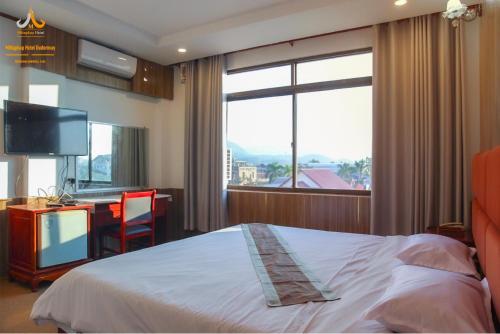 Mittaphap Hotel Oudomxai في موانج إكساي: غرفة نوم بسرير ومكتب وتلفزيون