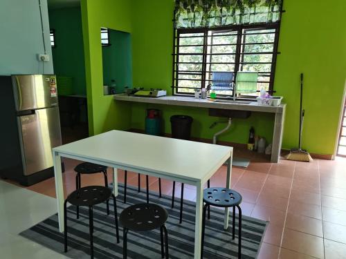 uma cozinha com uma mesa branca e dois bancos em Makmur Homestay Marang em Marang