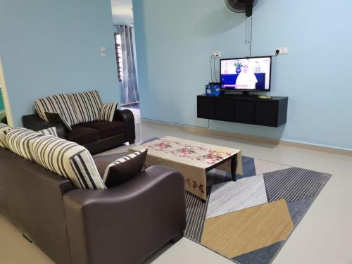 uma sala de estar com dois sofás e uma televisão em Makmur Homestay Marang em Marang