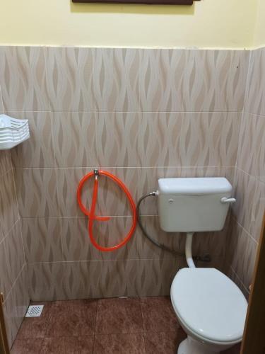 a bathroom with a toilet and a hose on the wall at Makmur Homestay Marang in Marang