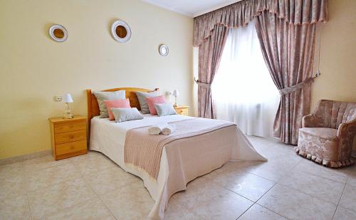 a bedroom with a bed and a window and a chair at Apartamentos Caleiro 6P - Vilanova de Arousa in Villanueva de Arosa