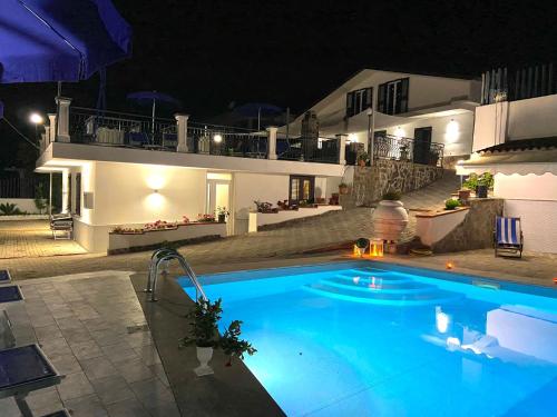 a swimming pool in front of a house at night at Serra Marina Rooms and Apartments in Santa Maria di Castellabate
