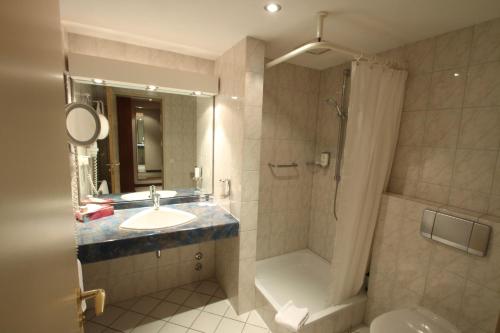 a bathroom with a sink and a shower and a toilet at Hotel Ratswaage in Magdeburg