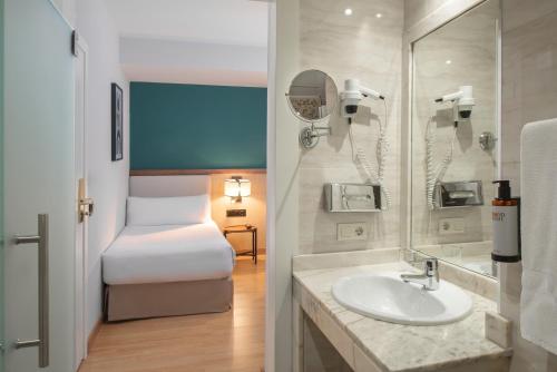 ein Bad mit einem Waschbecken und ein Bett in einem Zimmer in der Unterkunft Hotel Elche Centro , affiliated by Melia in Elche