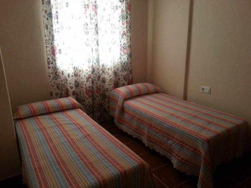 een kamer met twee eenpersoonsbedden en een raam bij Enjoy Life Chipiona in Chipiona