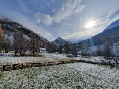 a snow covered field with a fence and mountains at Refuge Hôtel de Bayasse in Uvernet-Fours