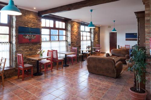 una sala de estar con mesas, sillas y una pared de ladrillo. en Hotel Gastronómico Cabo Vidío, en Oviñana