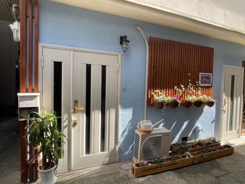 a blue wall with a door and a tv and plants at 距离Namba Shinsaibashi麗子民宿 in Osaka