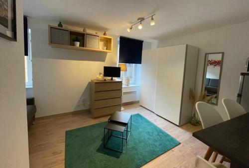 Studio zone piétonne à Saverne في سافيرن: غرفة معيشة صغيرة مع سجادة خضراء ومكتب