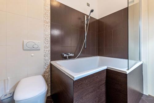 a bathroom with a bath tub and a toilet at Residence Virgilio Green in Toscolano Maderno