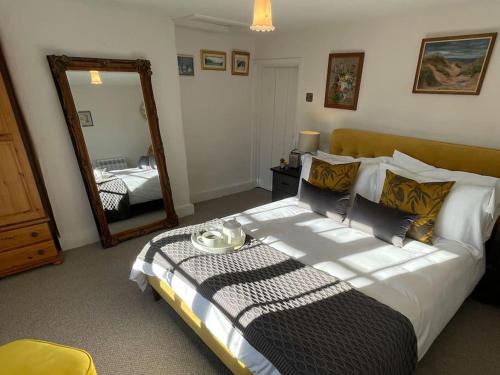 a bedroom with a large bed and a mirror at Elm Cottage in Northallerton