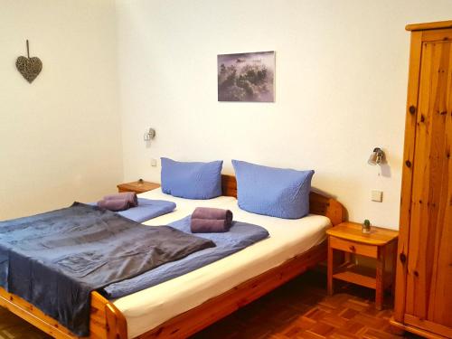 een slaapkamer met een groot bed met blauwe kussens bij Gästehaus Zum Weinbauer in Rhodt unter Rietburg