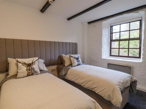 a bedroom with two beds and a window at The Eller Beck in Skipton
