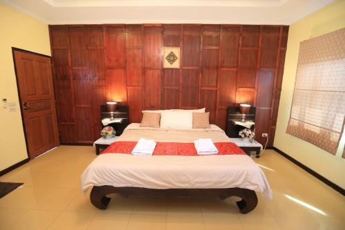 Schlafzimmer mit einem großen Bett und Holzwänden in der Unterkunft นอนในสวน รีสอร์ท in Bangkok