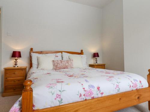 a bedroom with a bed with a floral bedspread and two lamps at Castle Cottage in Hythe