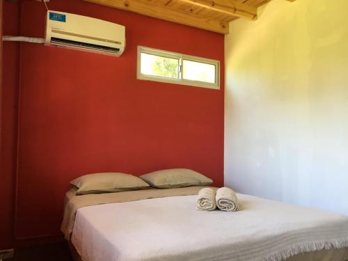 1 dormitorio con 2 camas y pared roja en El Limbo Posada en Tigre